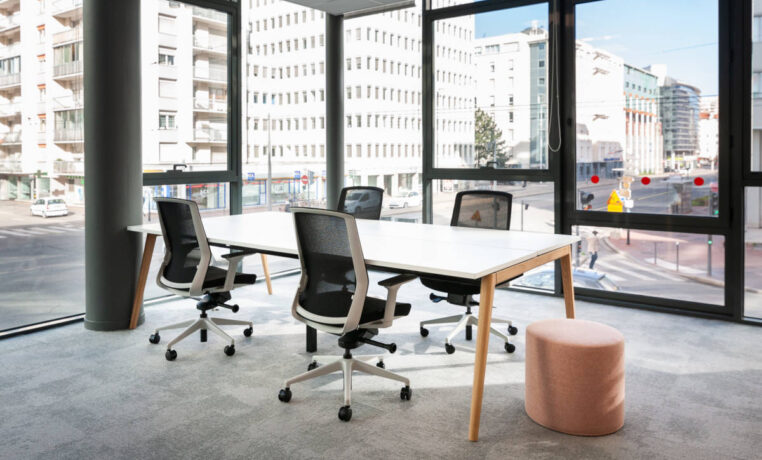 Bureau équipé d'une table Woodesk accompagnée de quatre sièges ergonomiques J1 et d'un pouf, offrant un espace de travail fonctionnel et confortable pour des sessions prolongées.