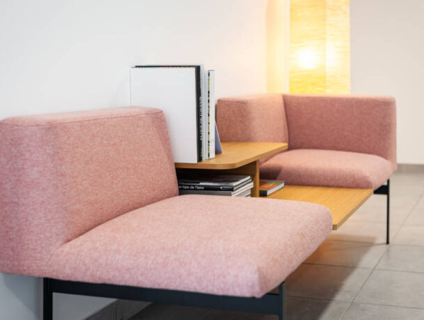 Deux fauteuils confortables disposés avec une table basse intégrée avec des magazines, créant un espace convivial et relaxant pour les pauses et les discussions informelles chez Techtera.