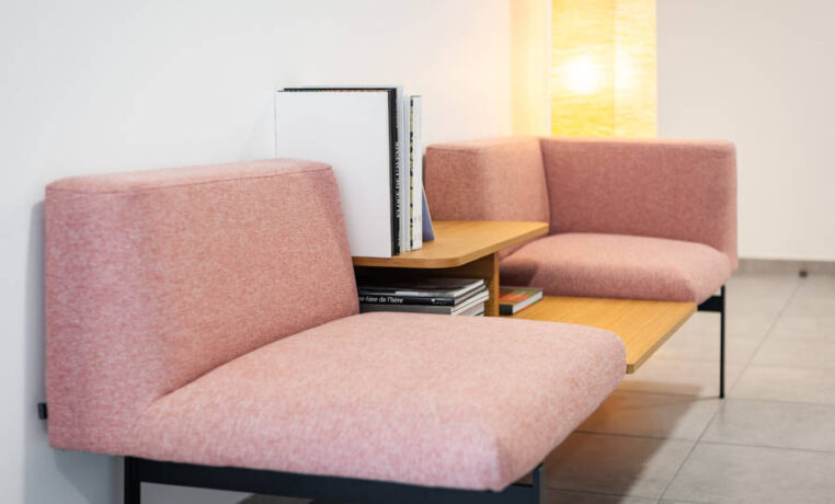 Deux fauteuils confortables disposés avec une table basse intégrée avec des magazines, créant un espace convivial et relaxant pour les pauses et les discussions informelles chez Techtera.