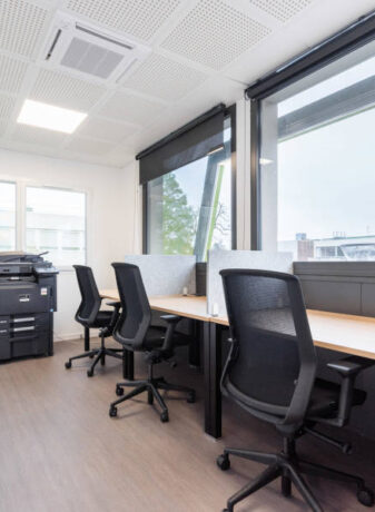 Espace de travail individuel avec bureaux U-Desk, sièges ergonomiques J1 et séparateurs entre les postes, offrant un environnement de travail personnel et bien organisé.