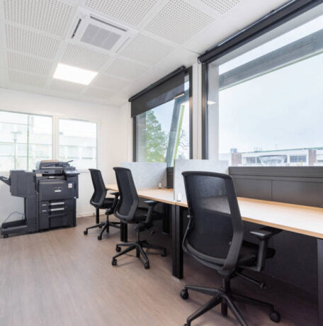 Espace de travail individuel avec bureaux U-Desk, sièges ergonomiques J1 et séparateurs entre les postes, offrant un environnement de travail personnel et bien organisé.