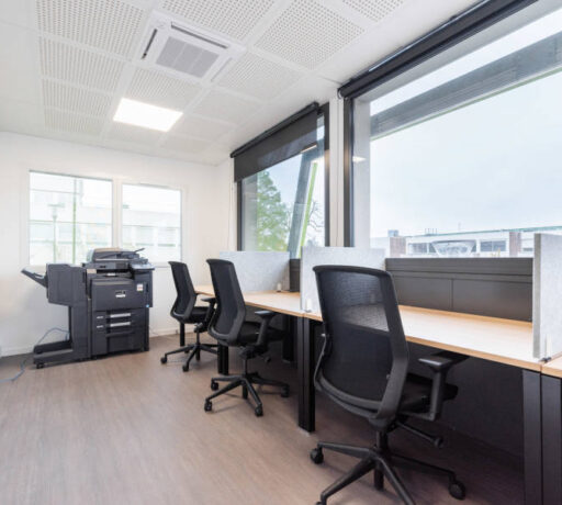 Espace de travail individuel avec bureaux U-Desk, sièges ergonomiques J1 et séparateurs entre les postes, offrant un environnement de travail personnel et bien organisé.