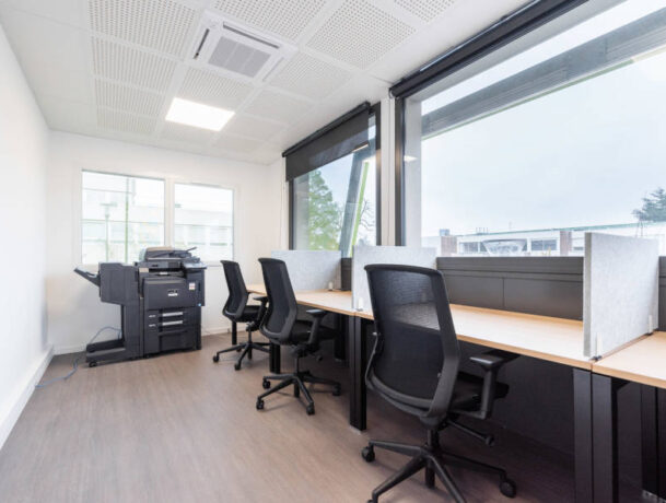 Espace de travail individuel avec bureaux U-Desk, sièges ergonomiques J1 et séparateurs entre les postes, offrant un environnement de travail personnel et bien organisé.