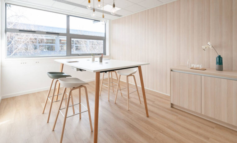 Espace de collaboration en bois avec une table haute et des tabourets multicolores, offrant un cadre dynamique et stimulant pour des sessions de travail en groupe.