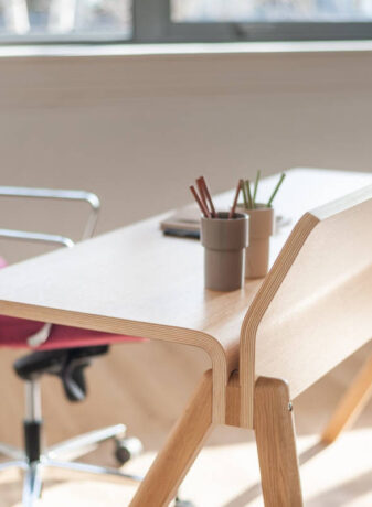 Bureau en bois élégant chez BOIRON accompagné d'un fauteuil en tissu rose, apportant une touche de couleur et de confort dans un espace de travail chic et fonctionnel.