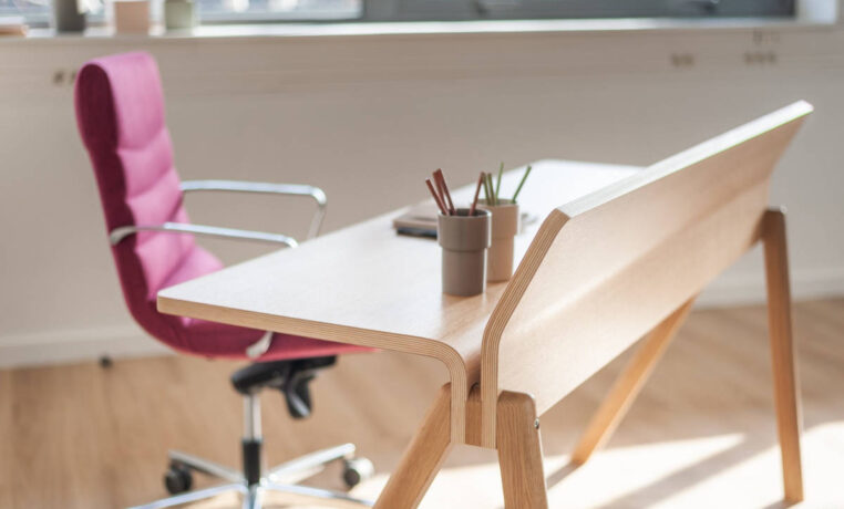 Bureau en bois élégant chez BOIRON accompagné d'un fauteuil en tissu rose, apportant une touche de couleur et de confort dans un espace de travail chic et fonctionnel.