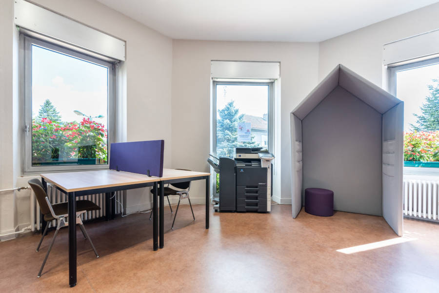 Vue sur un bureau dans l'espace de coworking, montrant un écran SILENS et une cabine, offrant un espace de travail privé dans un environnement partagé.