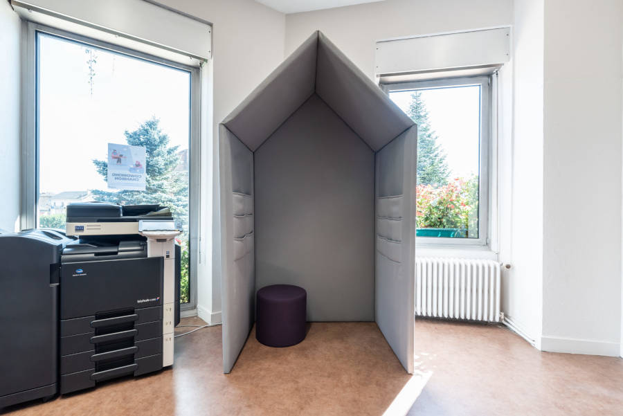 Cabine dans l'espace de coworking, équipée d'un pouf pour un espace de travail ou de repos privé et confortable.