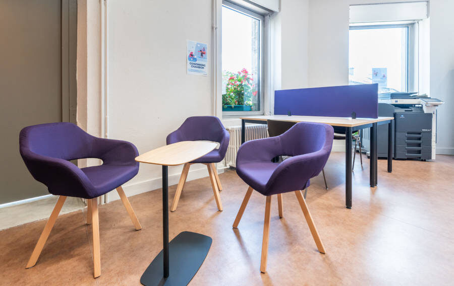 Espace détente dans l'espace de coworking, aménagé avec des chaises rembourrées confortables et une table WiFi, permettant aux utilisateurs de se reposer ou de travailler de manière informelle.