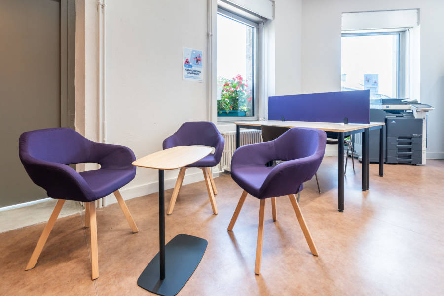 Espace détente dans l'espace de coworking, aménagé avec des chaises rembourrées confortables et une table WiFi, permettant aux utilisateurs de se reposer ou de travailler de manière informelle.