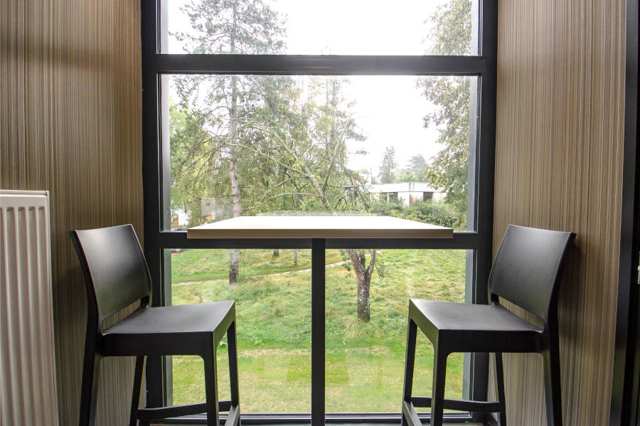 Table haute avec des tabourets dans un espace de travail flexible au CESI Arras, conçu pour encourager les discussions informelles et le travail collaboratif.