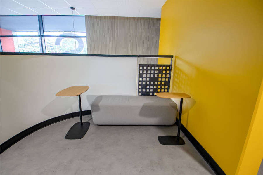 Espace détente au CESI Arras avec une banquette confortable et deux petites tables, permettant aux étudiants et aux collaborateurs de se reposer ou de discuter dans un cadre informel.