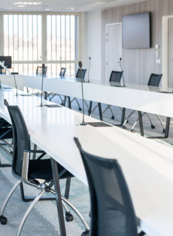 Grande salle de réunion moderne chez OPAC du Rhône, équipée d'une grande table de conférence entourée de chaises ergonomiques, idéale pour les réunions d'équipe et les présentations.