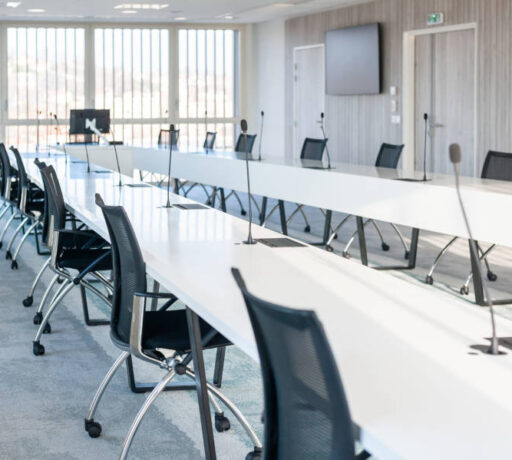 Grande salle de réunion moderne chez OPAC du Rhône, équipée d'une grande table de conférence entourée de chaises ergonomiques, idéale pour les réunions d'équipe et les présentations.