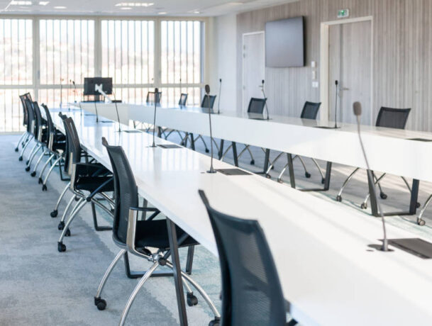 Grande salle de réunion moderne chez OPAC du Rhône, équipée d'une grande table de conférence entourée de chaises ergonomiques, idéale pour les réunions d'équipe et les présentations.