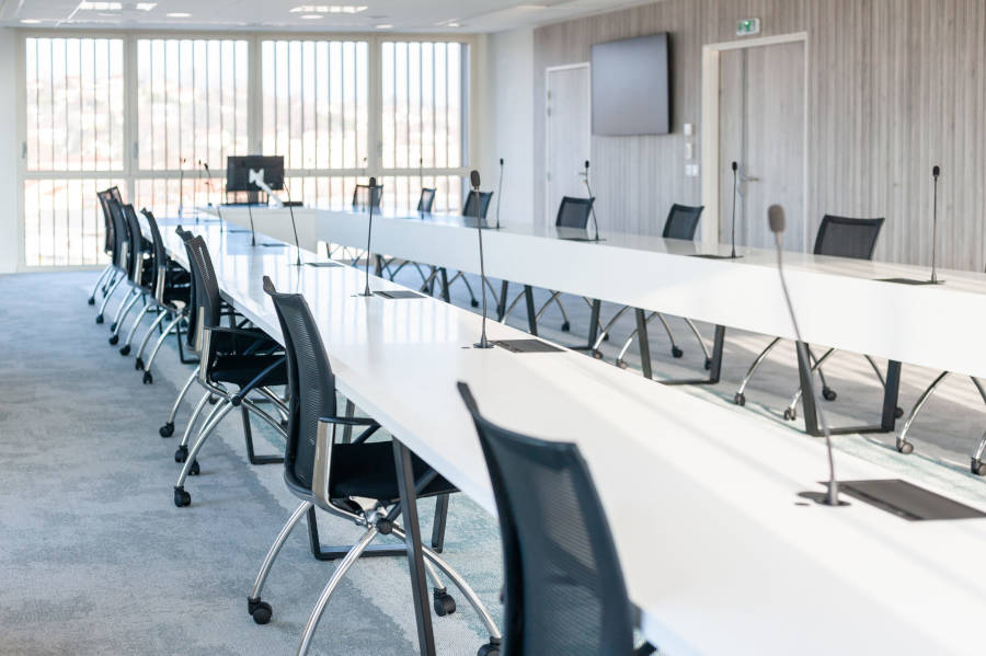 Grande salle de réunion moderne chez OPAC du Rhône, équipée d'une grande table de conférence entourée de chaises ergonomiques, idéale pour les réunions d'équipe et les présentations.