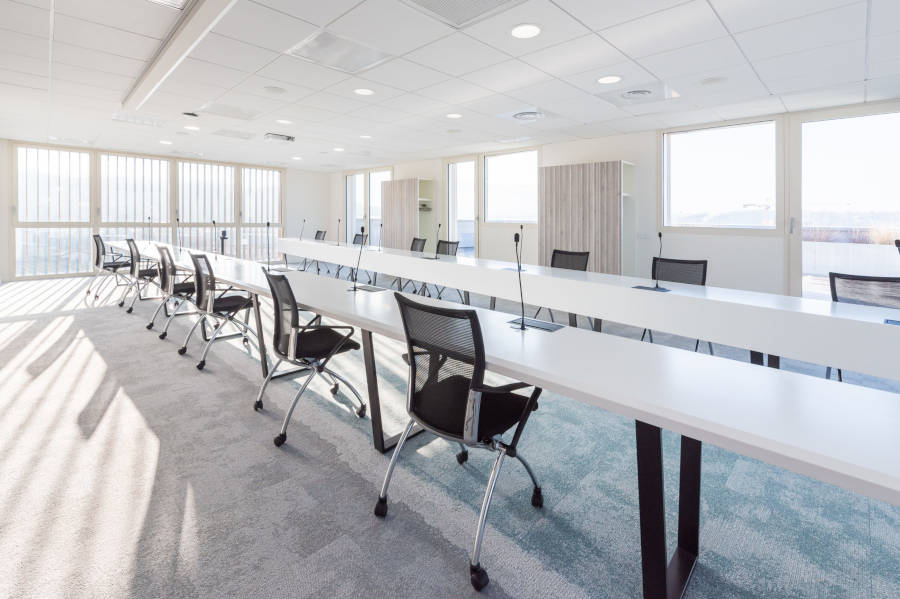 Salle de conférence chez OPAC du Rhône, montrant un espace moderne avec une table de conférence centrale, des chaises ergonomiques pour des réunions efficaces.