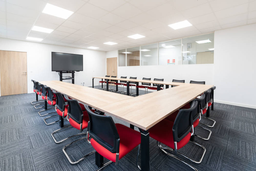 Salle de réunion chez Ariston, équipée d'une grande table de conférence entourée de chaises ergonomiques, créant un cadre idéal pour des réunions professionnelles et des présentations.