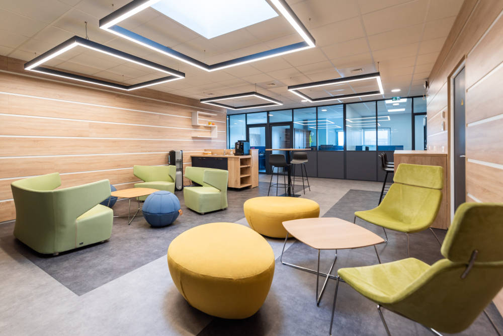 Espace détente chez Carbogen Amcis, aménagé avec des canapés modernes, des fauteuils SILENSE, des poufs HOP et des tables basses, créant un environnement relaxant pour les pauses et les échanges informels entre collègues.