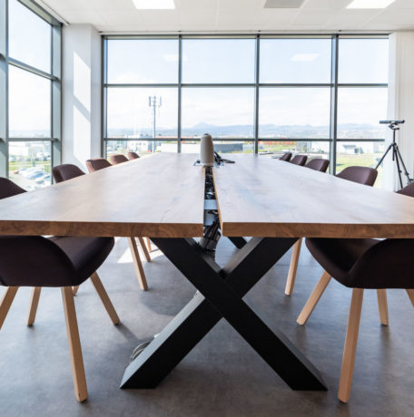 Salle de réunion lumineuse chez Carbogen Amcis, équipée d'une grande table en bois massif TIMBER entourée de fauteuils confortables, facilitant des réunions efficaces et des sessions de travail collaboratif.