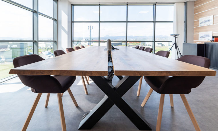 Salle de réunion lumineuse chez Carbogen Amcis, équipée d'une grande table en bois massif TIMBER entourée de fauteuils confortables, facilitant des réunions efficaces et des sessions de travail collaboratif.