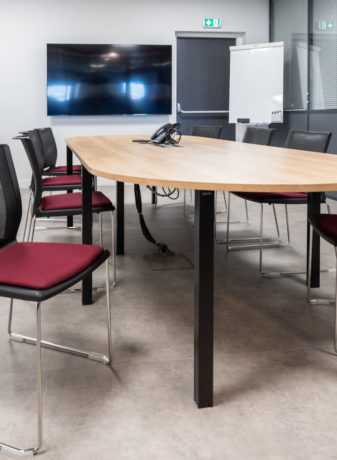 Salle de réunion chez Carbogen Amcis, dotée d'une grande table de conférence et de chaises confortables, offrant un cadre professionnel idéal pour des réunions importantes et des discussions en groupe.