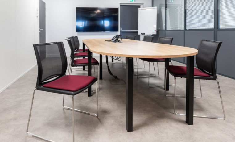 Salle de réunion chez Carbogen Amcis, dotée d'une grande table de conférence et de chaises confortables, offrant un cadre professionnel idéal pour des réunions importantes et des discussions en groupe.