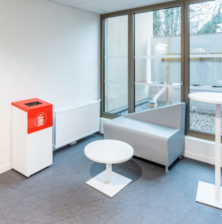 Espace de pause chez Département du Rhône aménagé avec un canapé confortable, une table basse Linéa, une table haute Linéa et un container poubelle, idéal pour les moments d'attente.