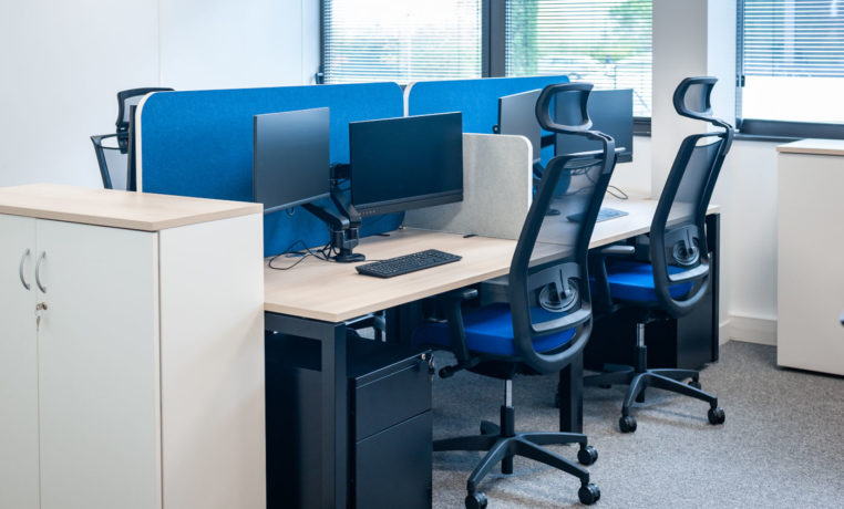 Open space avec des bureaux U-Desk séparés par des écrans acoustiques SILENS, complété par des caissons de rangement et un siège ergonomique, créant un environnement de travail moderne et fonctionnel.