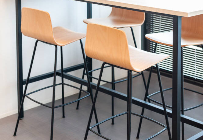 Table haute avec tabourets dans le réfectoire du Leader Mondial de Production de Transducteurs, offrant un espace moderne et pratique pour les repas rapides et les pauses café, tout en favorisant des interactions informelles entre collègues.