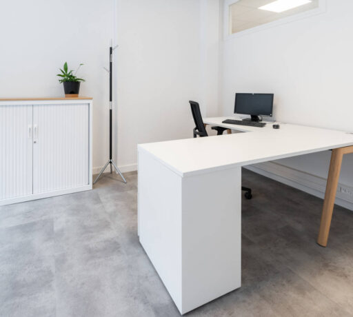 Bureau individuel chez Deltalys, équipé d'un écran d'ordinateur, d'un bureau Woodersk avec droit avec retour sur caisson 3 tiroirs, d'un siège ergonomique et une armoire avec un top de finition, offrant un espace de travail personnel tout en préservant la concentration.