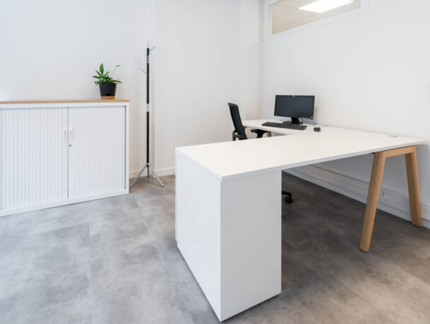 Bureau individuel chez Deltalys, équipé d'un écran d'ordinateur, d'un bureau Woodersk avec droit avec retour sur caisson 3 tiroirs, d'un siège ergonomique et une armoire avec un top de finition, offrant un espace de travail personnel tout en préservant la concentration.