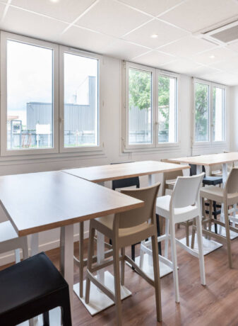 Réfectoire chez Deltalys, aménagé avec des tables hautes Linéa et des tabourets confortables, offrant un espace moderne et convivial pour les repas et les pauses.