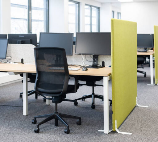 Open space Auvalie avec des bureaux U-Desk, des sièges ergonomiques et des séparateurs acoustiques sur pieds, créant un environnement de travail organisé et silencieux.