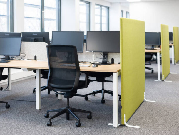 Open space Auvalie avec des bureaux U-Desk, des sièges ergonomiques et des séparateurs acoustiques sur pieds, créant un environnement de travail organisé et silencieux.