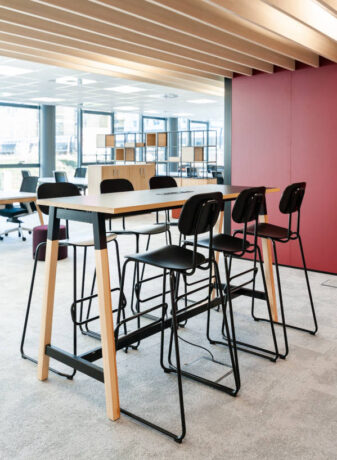 Espace de collaboration moderne avec une table haute et des tabourets, favorisant les échanges et les sessions de travail en groupe dans un environnement stimulant.