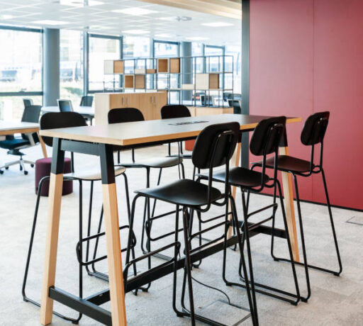 Espace de collaboration moderne avec une table haute et des tabourets, favorisant les échanges et les sessions de travail en groupe dans un environnement stimulant.