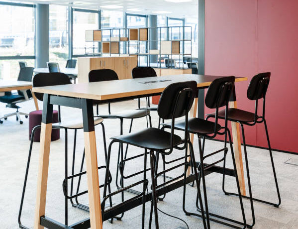 Espace de collaboration moderne avec une table haute et des tabourets, favorisant les échanges et les sessions de travail en groupe dans un environnement stimulant.