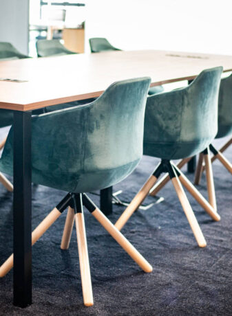 Salle de réunion élégante équipée d'une table Quattro et de fauteuils en velours, offrant un cadre raffiné et confortable pour des réunions importantes et des présentations.