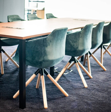 Salle de réunion élégante équipée d'une table Quattro et de fauteuils en velours, offrant un cadre raffiné et confortable pour des réunions importantes et des présentations.