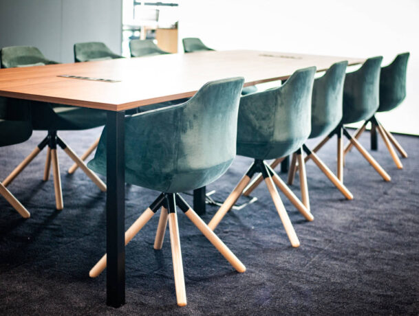 Salle de réunion élégante équipée d'une table Quattro et de fauteuils en velours, offrant un cadre raffiné et confortable pour des réunions importantes et des présentations.