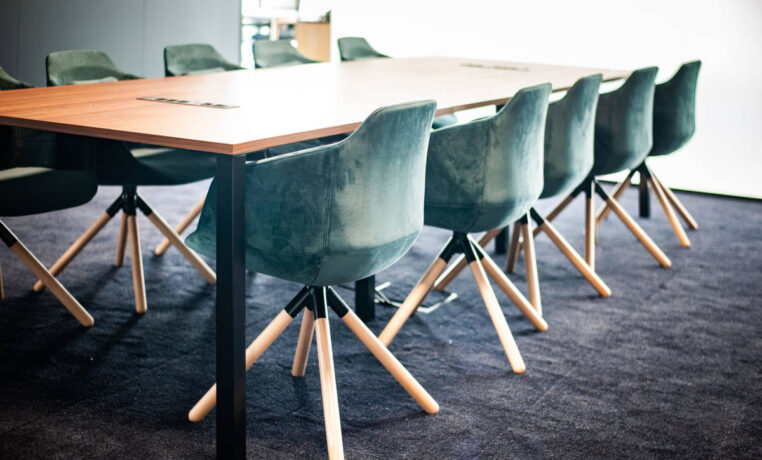 Salle de réunion élégante équipée d'une table Quattro et de fauteuils en velours, offrant un cadre raffiné et confortable pour des réunions importantes et des présentations.