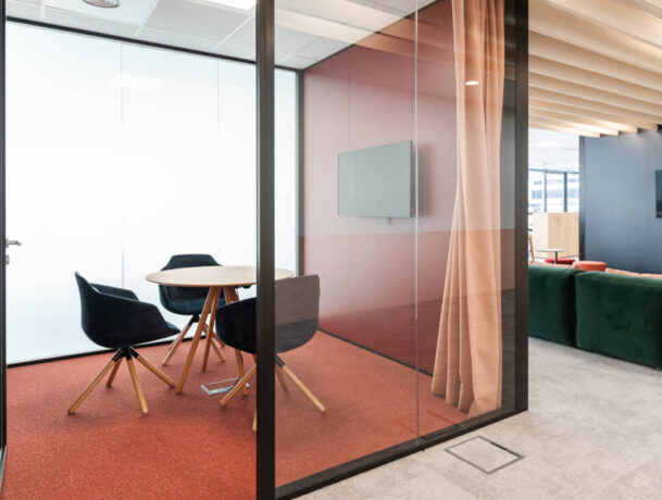 Petite salle de réunion équipée d'une table élégante entourée de trois fauteuils confortables, offrant un espace intime et professionnel pour des discussions en petit comité.