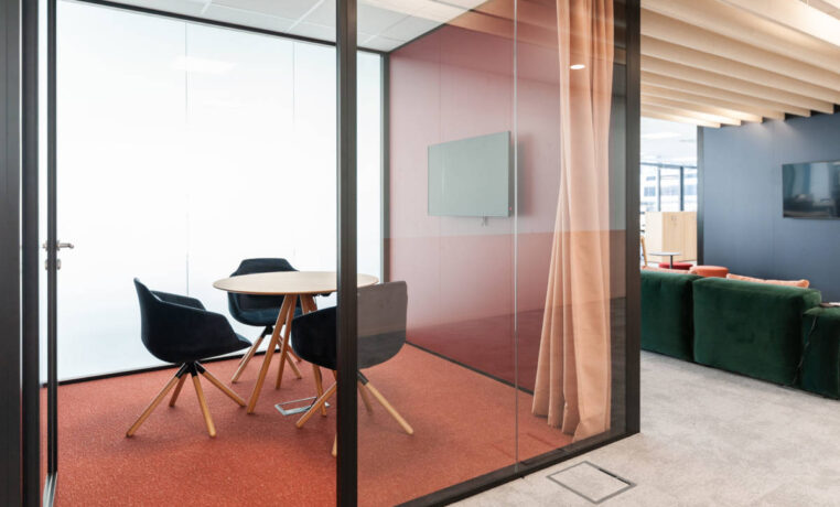 Petite salle de réunion équipée d'une table élégante entourée de trois fauteuils confortables, offrant un espace intime et professionnel pour des discussions en petit comité.