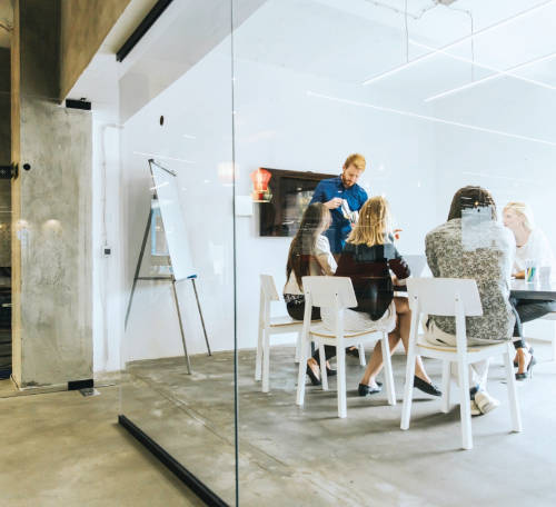 Salle de réunion avec des collaborateurs engagés dans une discussion active autour d'une table, illustrant un environnement propice à la collaboration et aux échanges d'idées.