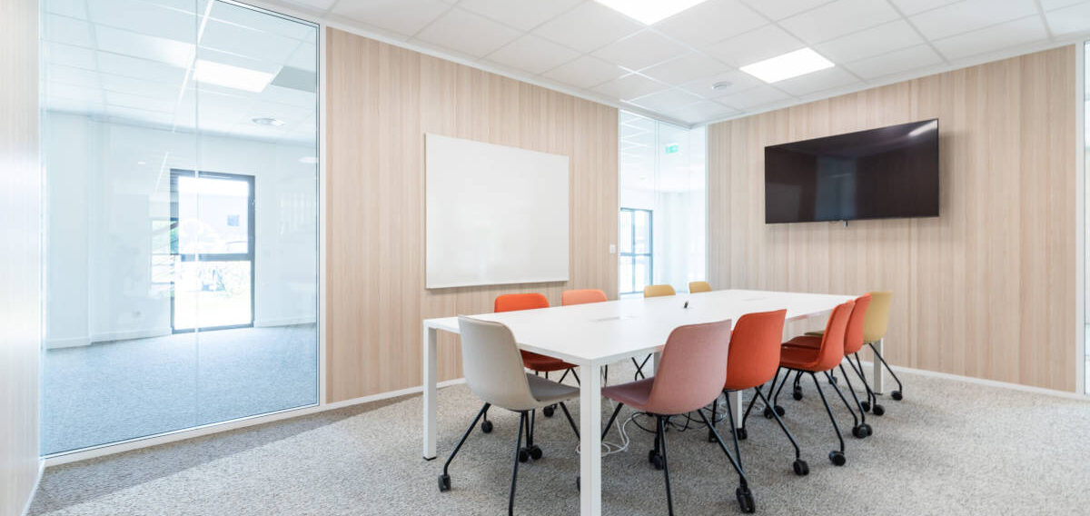 Salle de réunion élégante équipée d'une table U-DESK et de chaises Versus à roulettes, offrant un espace fonctionnel et flexible pour des réunions professionnelles.