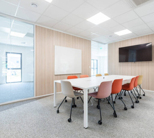 Salle de réunion élégante équipée d'une table U-DESK et de chaises Versus à roulettes, offrant un espace fonctionnel et flexible pour des réunions professionnelles.